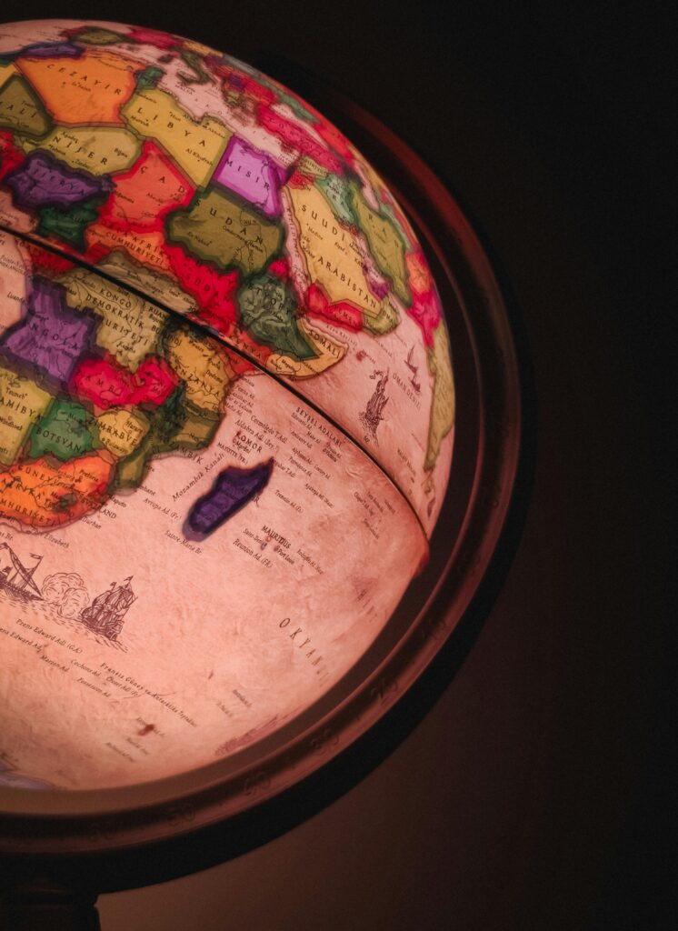 A glowing, vintage-style globe showcasing a colorful political map against a dark background.